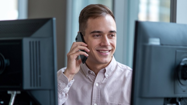 Cleveland security monitoring professional smiling during phone call in modern office environment